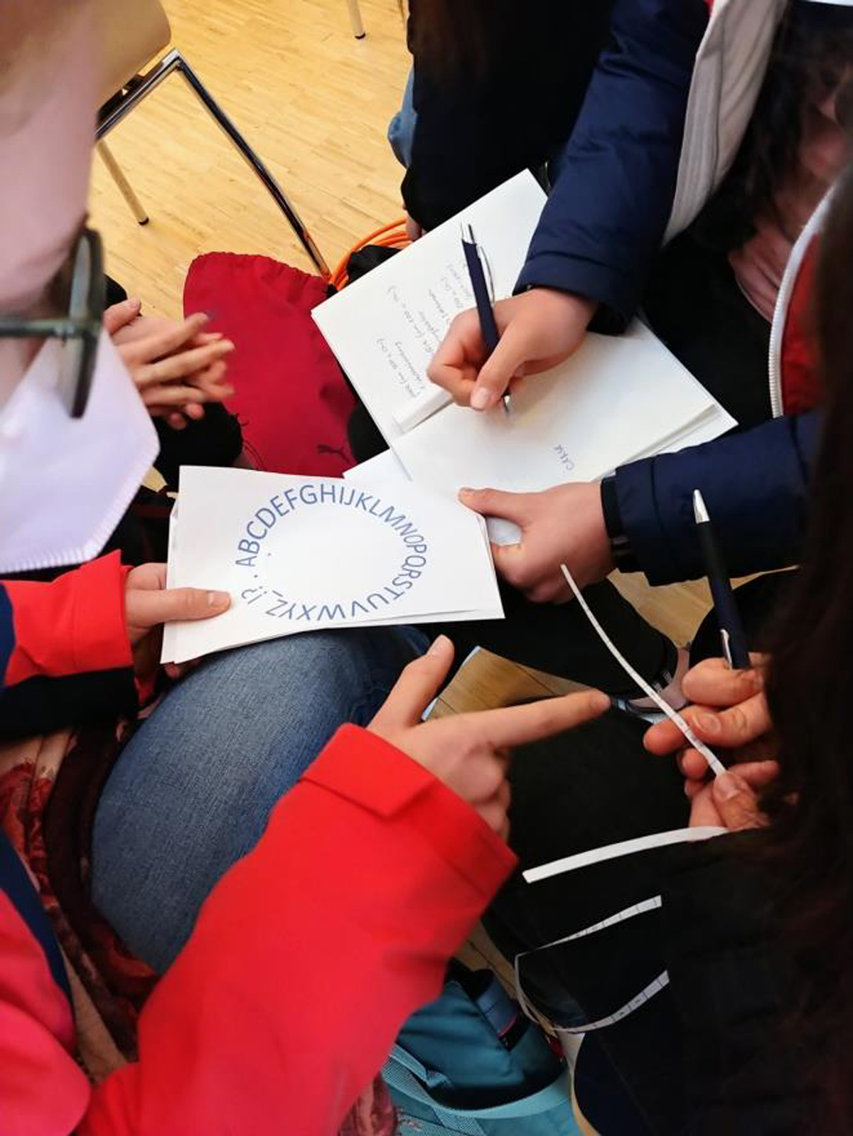 Schüler schauen alle auf ein Blatt Papier mit einem IT-Verschlüsselungs-Rätsel