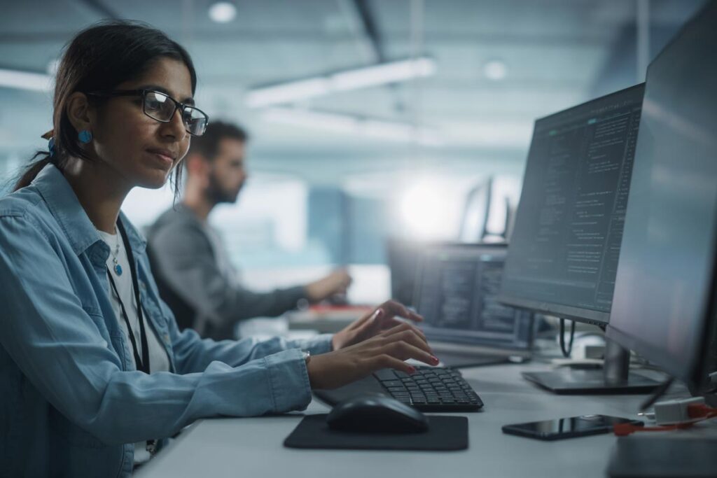 Mädchen sitzt im Büro am PC und tippt auf Tastatur