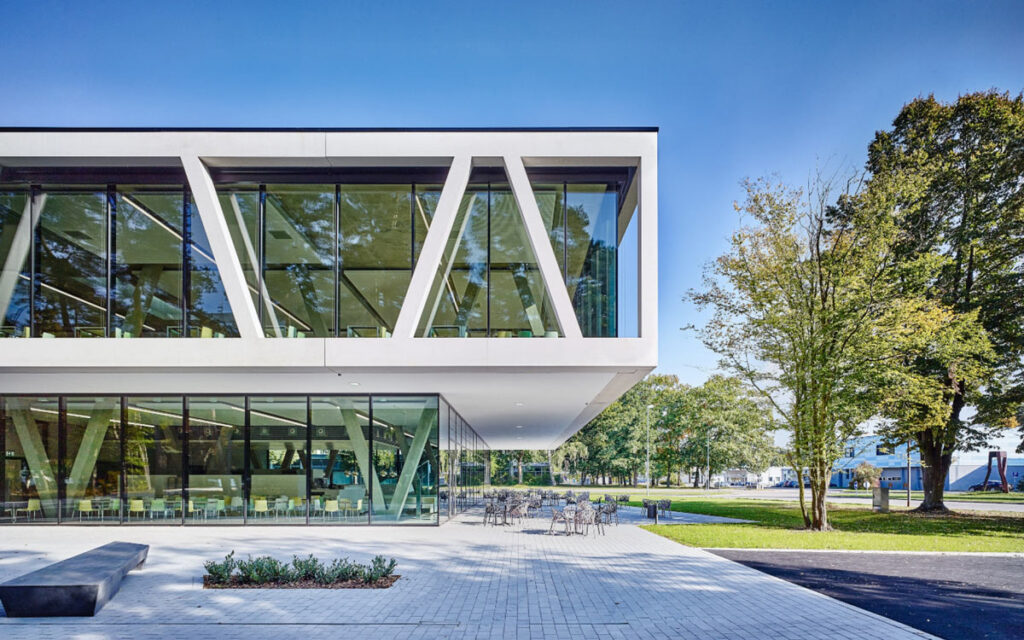 Ein modernes Bürogebäude mit großen Glasfronten neben einer Grünfläche