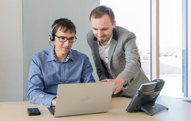 Two men look into a laptop together