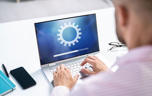 A man sits in front of a laptop and types something