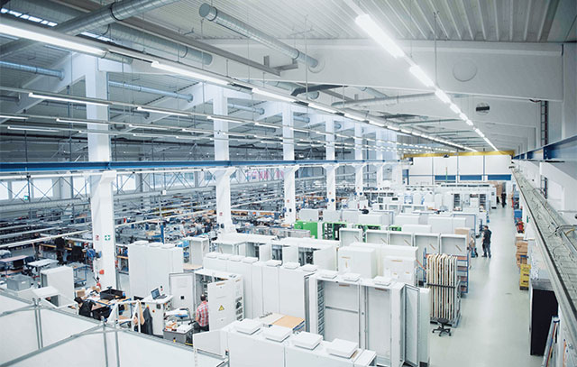 A well-lit hall with many white cabinets and working employees