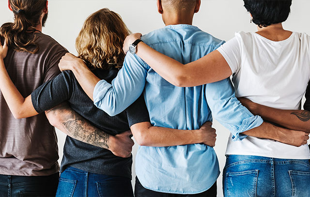 A group of different people holding each other in their arms