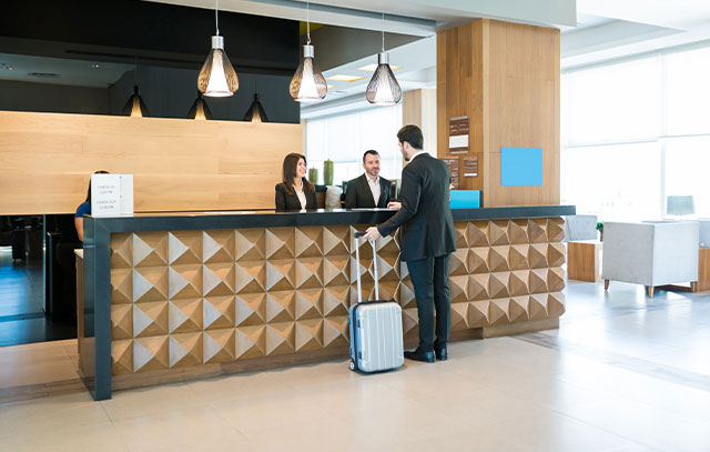 A man stands at the hotel reception with his suitcase