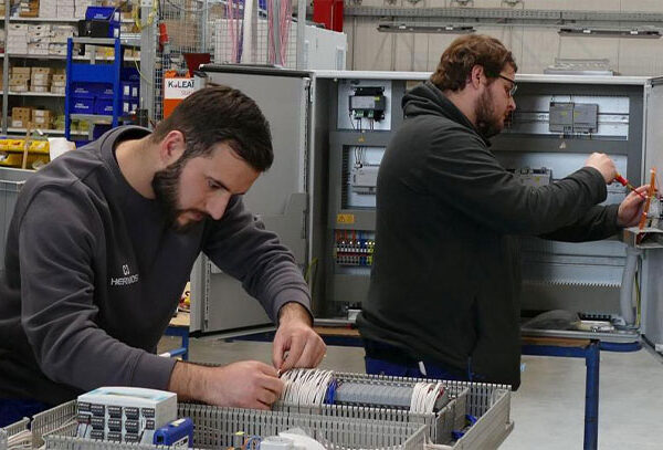 Two young men work on a control cabinet