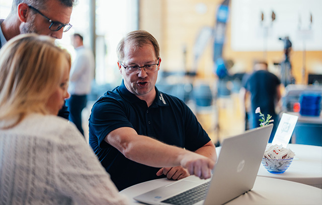 A HERMOS employee explains something on a laptop to two people